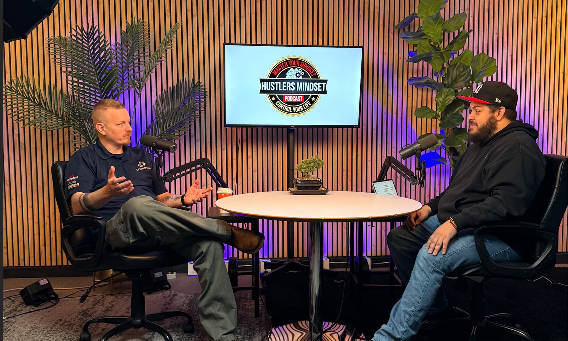 Two guests recording a podcast episode at the studio desk